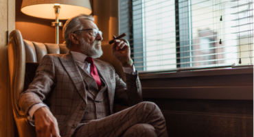 A Wealthy man sitting with a cigar contemplating the strategies of the rich and wealthy